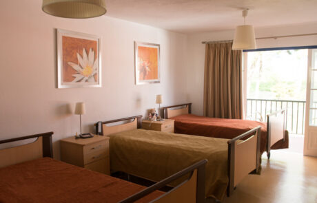 Quarto com 3 camas e dois quadros com flores