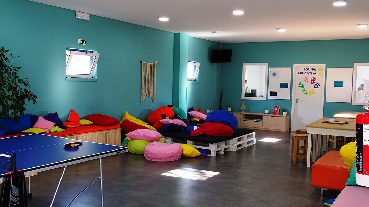 Sala com puffs, mesas e cadeiras e uma mesa de ping pong